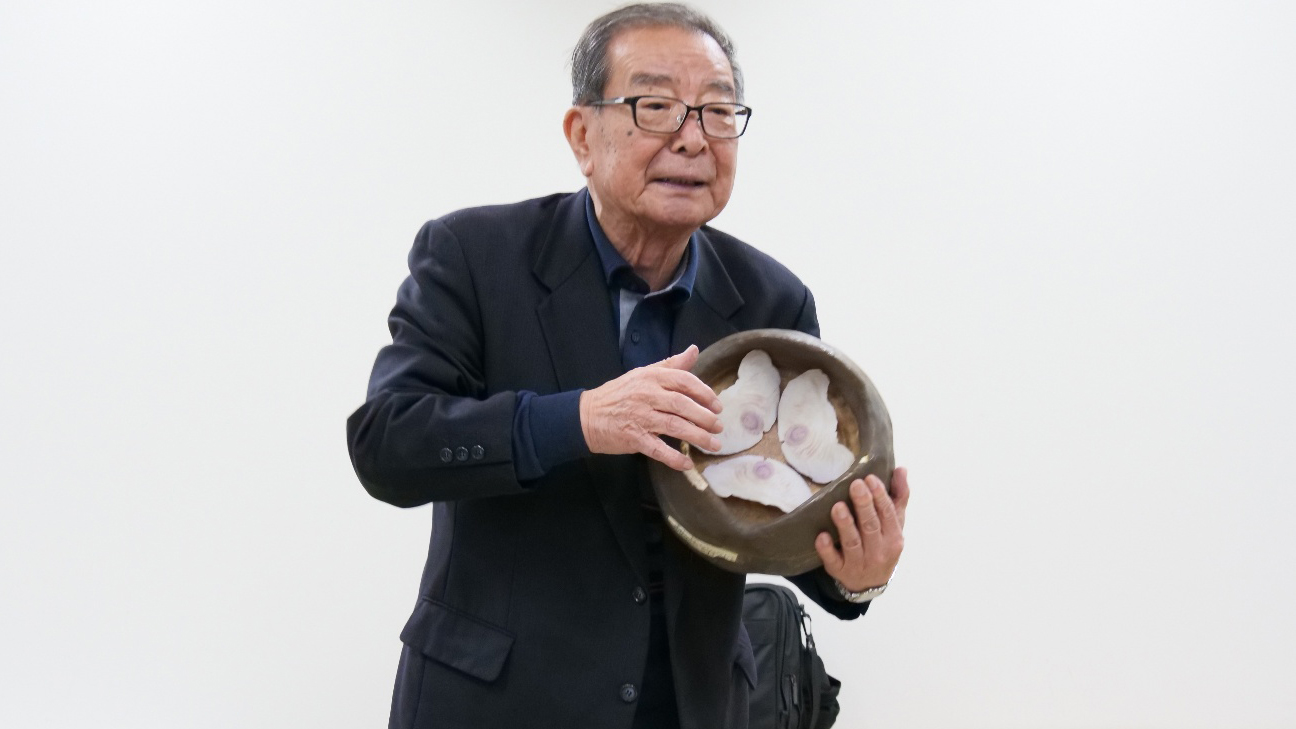 タネの模型を持って説明する矢野氏の写真